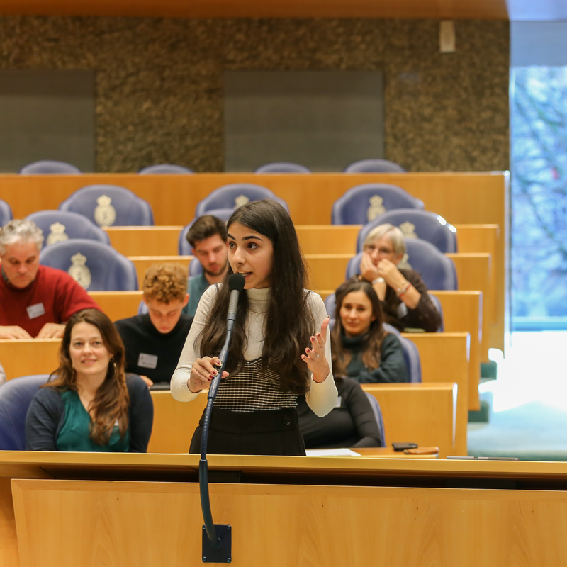 Een jonge vrouw staat achter de interruptiemicrofoon van de Tweede Kamer